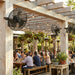 People dining under a wooden pergola with MULE outdoor fans