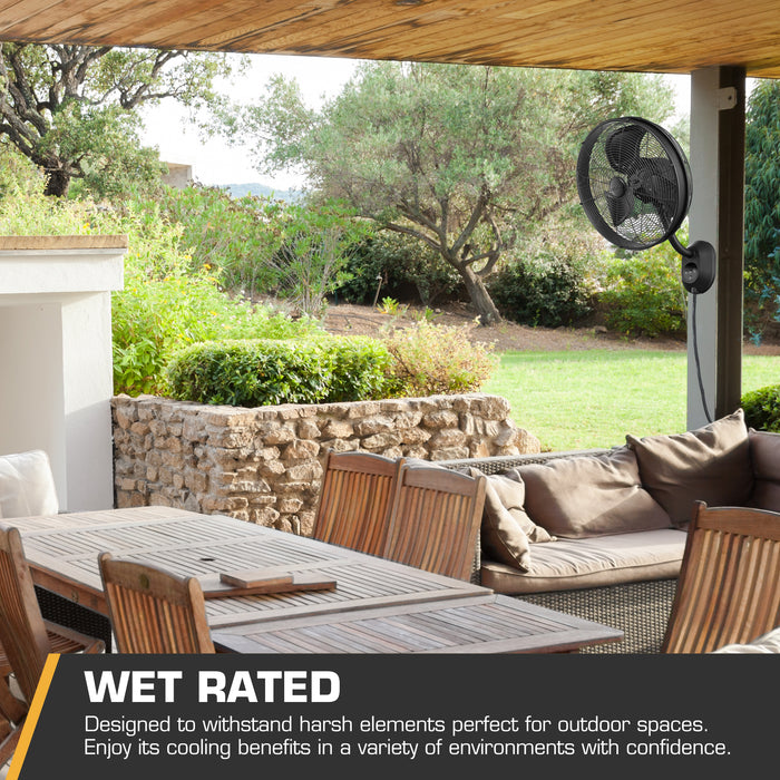 Outdoor patio with furniture and a Mule wet rated fan, surrounded by greenery.
